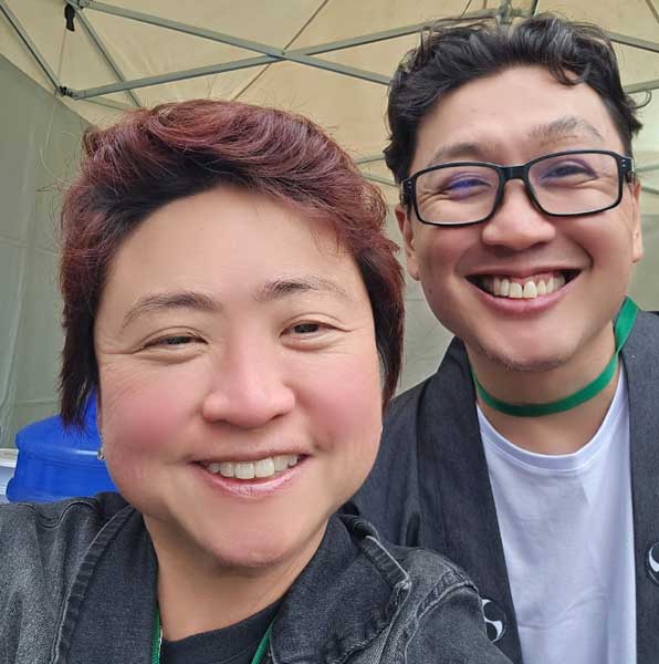 Duas pessoas japonesas posando para a câmera, um homem e uma mulher sorridentes.